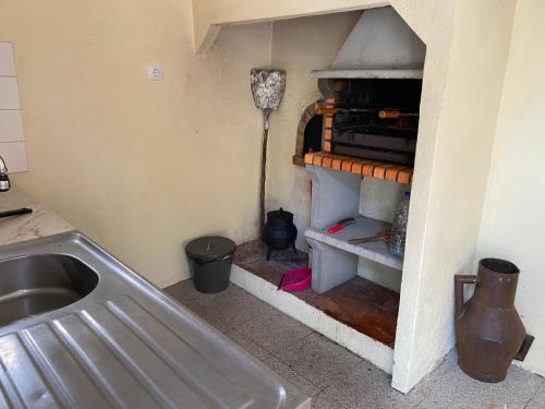 uma cozinha com um lavatório e uma prateleira com uma vassoura em Quinta dos Pinheiros em Estanqueiro