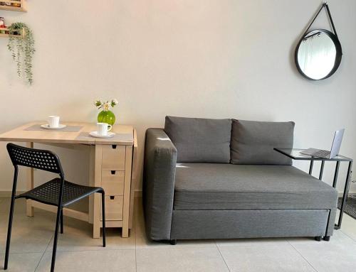 a couch and a desk with a chair and a table with a laptop at Life ATMOsphäre Apartment Lahr-Schwarzwald in Lahr