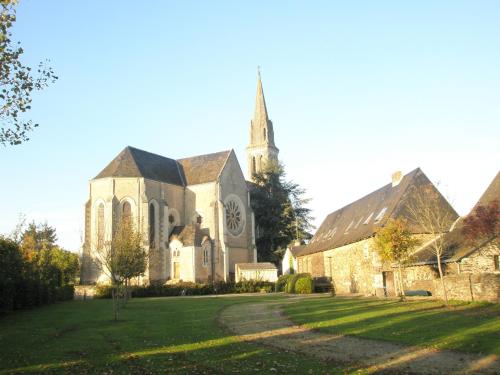 an old church with a steeple and a grass yard at Grange du Plessis in Segré