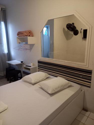 1 dormitorio con cama blanca y espejo en la pared en Hotel Prince, en São Paulo
