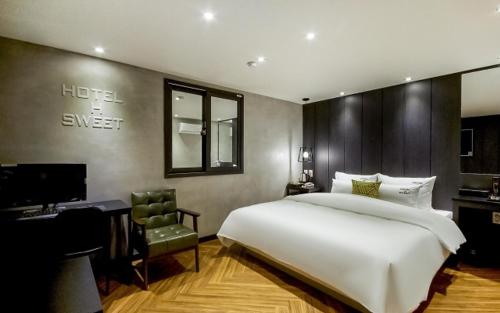 釜山的住宿－Hotel the Sweet，卧室配有一张白色大床和一张书桌
