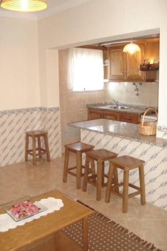 a kitchen with a table and some chairs and a counter at Casas do Castelo in Aldeia da Serra