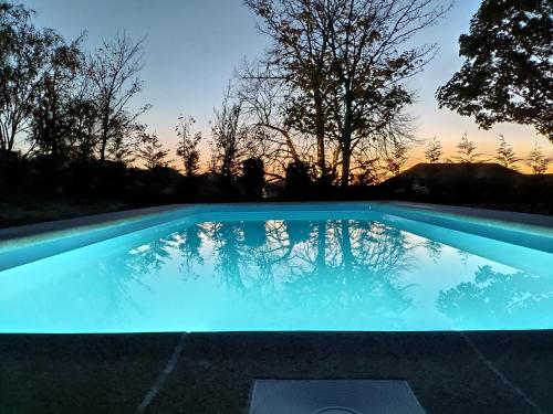 a swimming pool with a sunset in the background at Quinta Chão da Bispa in Oliveira do Hospital