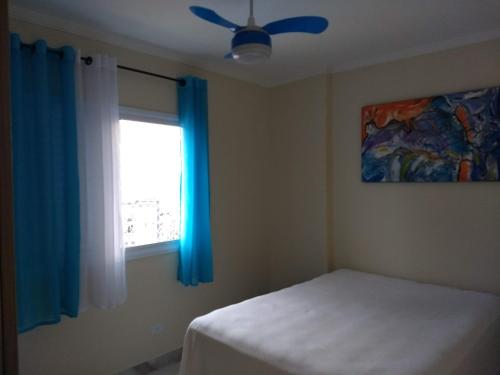 Un dormitorio con una cama y una ventana con cortinas azules. en Apto Azul Oceano, en Mongaguá