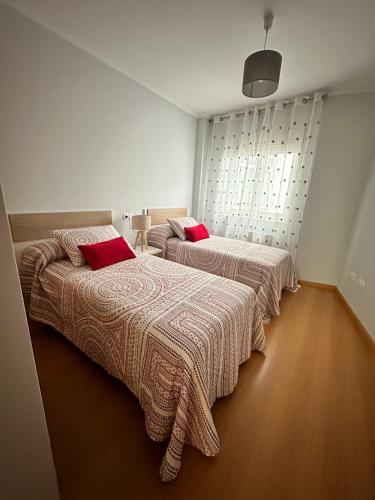 two beds with red pillows in a room at Apartamento Ría de Arousa in Boiro