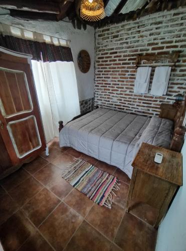 a bedroom with a bed and a brick wall at Cabañas El Molino in Potrerillos