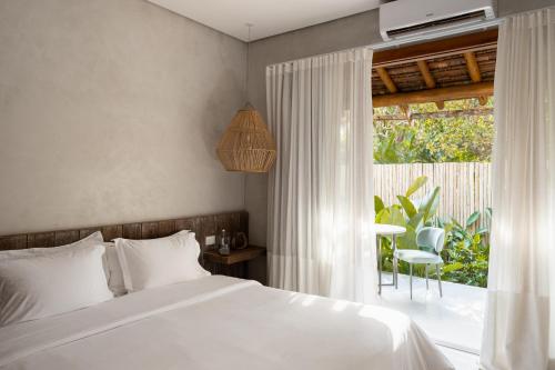 a bedroom with a white bed and a window at Vila Almesca in Caraíva