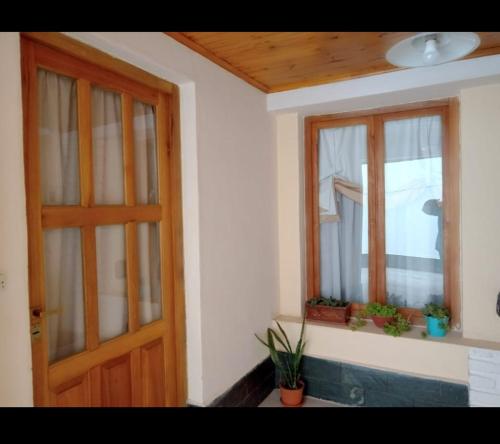 Habitación con 2 ventanas y puerta de madera. en Departamento Del Sol (Esquel-Chubut) en Esquel