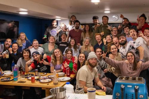 een groep mensen die poseren voor een foto aan een tafel bij Adventure Q2 Hostel in Queenstown