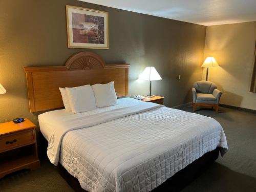 a hotel room with a large bed and a chair at Americas Best Value Inn Pharr/McAllen in Pharr