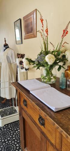 een houten tafel met een vaas met bloemen erop bij The Nurses Home Guesthouse - Reefton in Reefton