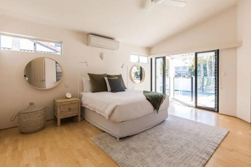 a bedroom with a large bed and a mirror at The River House includes a private beach jetty and pool in Noosa Heads