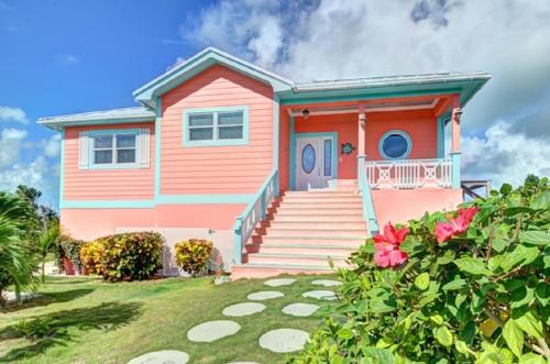 uma casa cor-de-rosa com um alpendre e um quintal em Savannah Sunset home em Savannah Sound