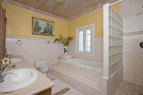 y baño con bañera, aseo y lavamanos. en Long Island Breeze Compound home en Nassau