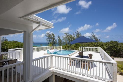 a balcony with a pool and an umbrella at Come and Go Villa home in Hatchet Bay Limited Settlement