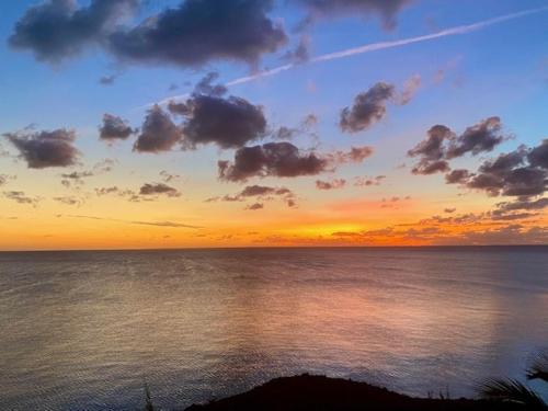 una puesta de sol sobre un cuerpo de agua con en Blue Love Point home, en Gregory Town