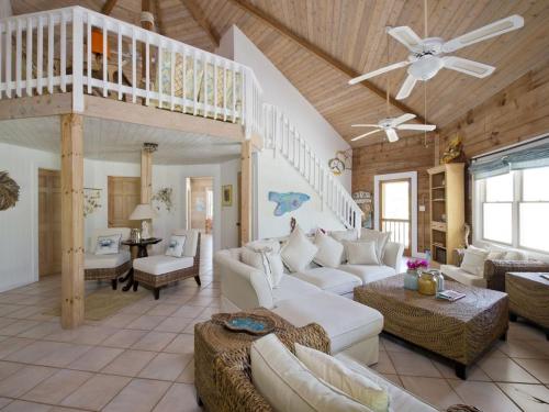 uma sala de estar com mobiliário branco e um tecto de madeira em Shangri-La & Orchid Cottage home em Governorʼs Harbour