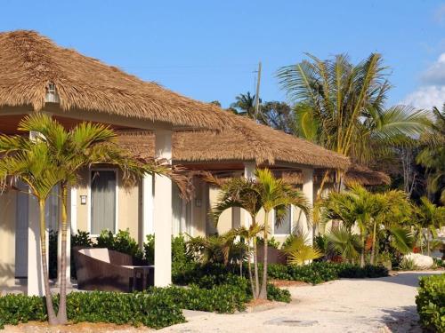 una casa con palmeras delante en Sky Beach Club Bungalow cabin, en Governorʼs Harbour
