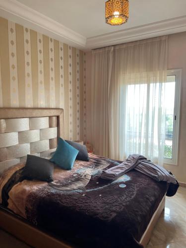 a bedroom with a large bed with blue pillows at Ricoflores PALM in Ben Slimane