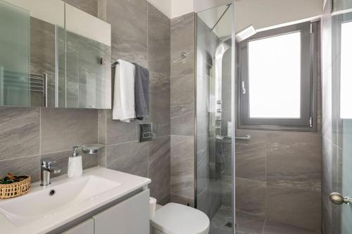 La salle de bains est pourvue de toilettes, d'un lavabo et d'une douche. dans l'établissement Elea Kallithea Apartment. Acropolis & Sea View, à Athènes