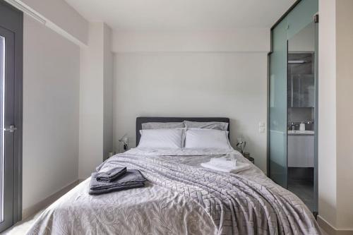 a white bedroom with a bed with a mirror at Elea Kallithea Apartment. Acropolis & Sea View in Athens