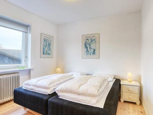 a bedroom with a bed with white sheets and a window at Holiday home Strandby XII in Strandby