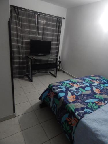 Excelente ubicación في بوكارامانغا: غرفة نوم بسرير وتلفزيون على طاولة