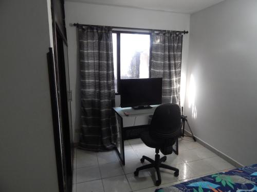Excelente ubicación في بوكارامانغا: غرفة نوم مع مكتب مع جهاز كمبيوتر ونافذة