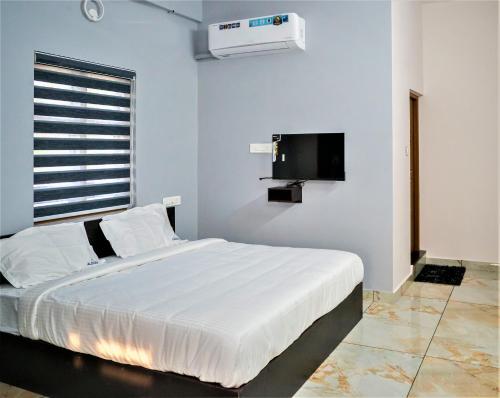 a bedroom with a white bed and a tv at Aldora Airport Residency in Nedumbassery