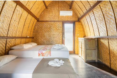 um quarto com duas camas numa casa de bambu em Deep House Bungalows em Gili Trawangan