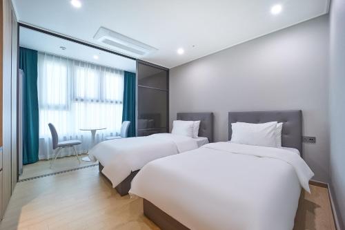 a hotel room with two beds and a table at Jeonju Signature Hotel&Residence in Jeonju