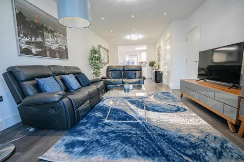 a living room with a leather couch and a flat screen tv at Newly Refurbished Modern 4 Bed Detached House ! in Oxford