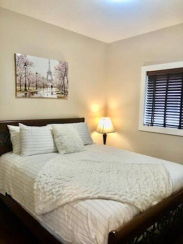 a bedroom with a bed and a lamp and a window at Luxury 3700 sq/ 5 bedroom/ jettedtub/ 4 fireplaces in Edmonton