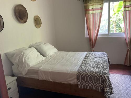 Pretty house Bastimentos Bocas del toro في باستيمينتوس: غرفة نوم بسرير وملاءات بيضاء ونافذة