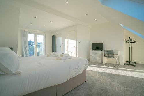a white bedroom with a large bed and a television at Newly Refurbished Modern 4 Bed Detached House ! in Oxford