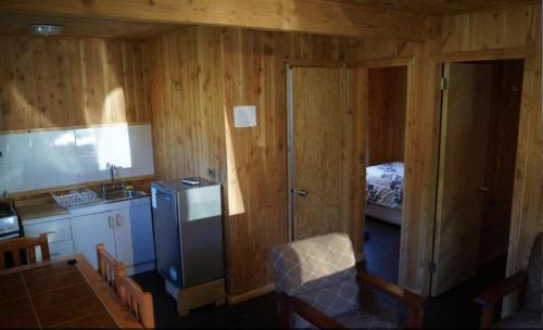 a kitchen with a refrigerator and a bed in a room at Cabañas-apartamentos Borde Río in Neltume