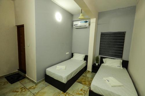 a small room with two beds and a window at Aldora Airport Residency in Nedumbassery
