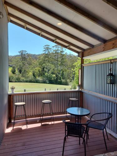 a porch with a table and chairs on a deck at Bellingen Guest Suite with Forest Views in Brierfield
