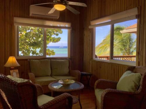 a living room with a couch and a table and two windows at Beachfront Home With Pristine, Calm Waters, White Sands And Unbelievable Sunset in Sandy Bay