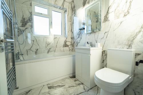 a bathroom with a toilet and a tub and a sink at Newly Refurbished Modern 4 Bed Detached House ! in Oxford