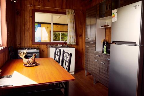 a kitchen with a wooden table and a refrigerator at CABAÑA AZUL Y VERDE in Ancud