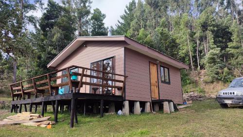 ein Haus mit einer Terrasse und einem davor geparkt in der Unterkunft Cabañas Isla Del rey in Valdivia