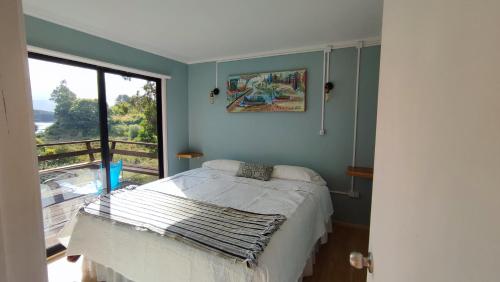 a bedroom with a bed and a large window at Cabañas Isla Del rey in Valdivia