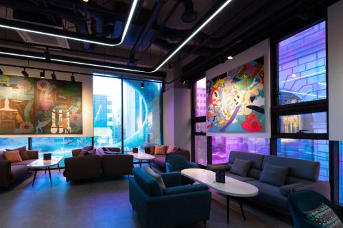 a waiting room with couches and tables and paintings at Aiden by Best Western Cheongdam in Seoul