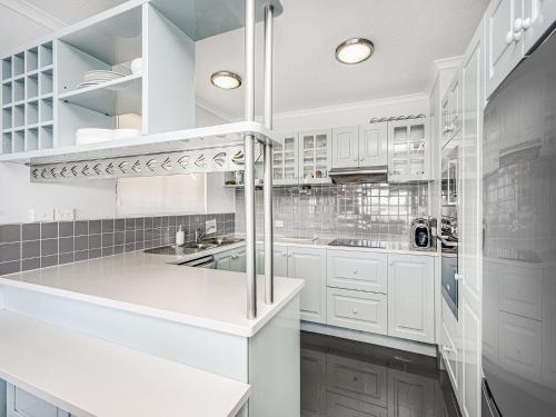 a white kitchen with white cabinets and a sink at Pumicestone Quays by Luxury Escapes Caloundra in Caloundra