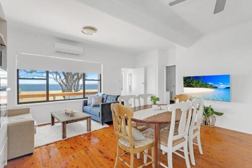 a dining room and living room with a table and chairs at Waterfront Fishermans Cottage in Erowal Bay
