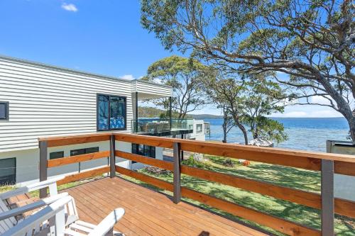 a house with a deck with a view of the ocean at Waterfront Fishermans Cottage in Erowal Bay