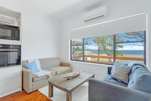a living room with a couch and a table at Waterfront Fishermans Cottage in Erowal Bay