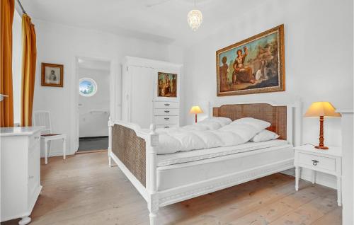 Un dormitorio con una cama blanca y una pintura en la pared en Baronessens Enkesde en Hornslet
