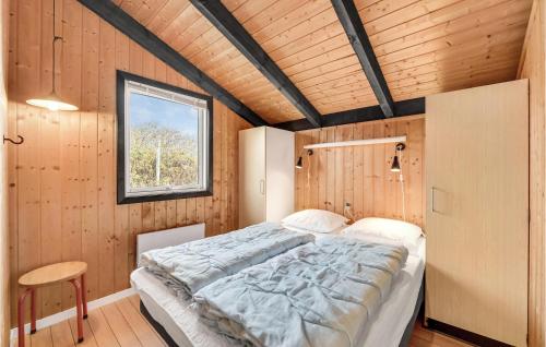BjerregårdにあるAmazing Home In Hvide Sande With Wifiの木製の部屋にベッド1台が備わるベッドルーム1室があります。